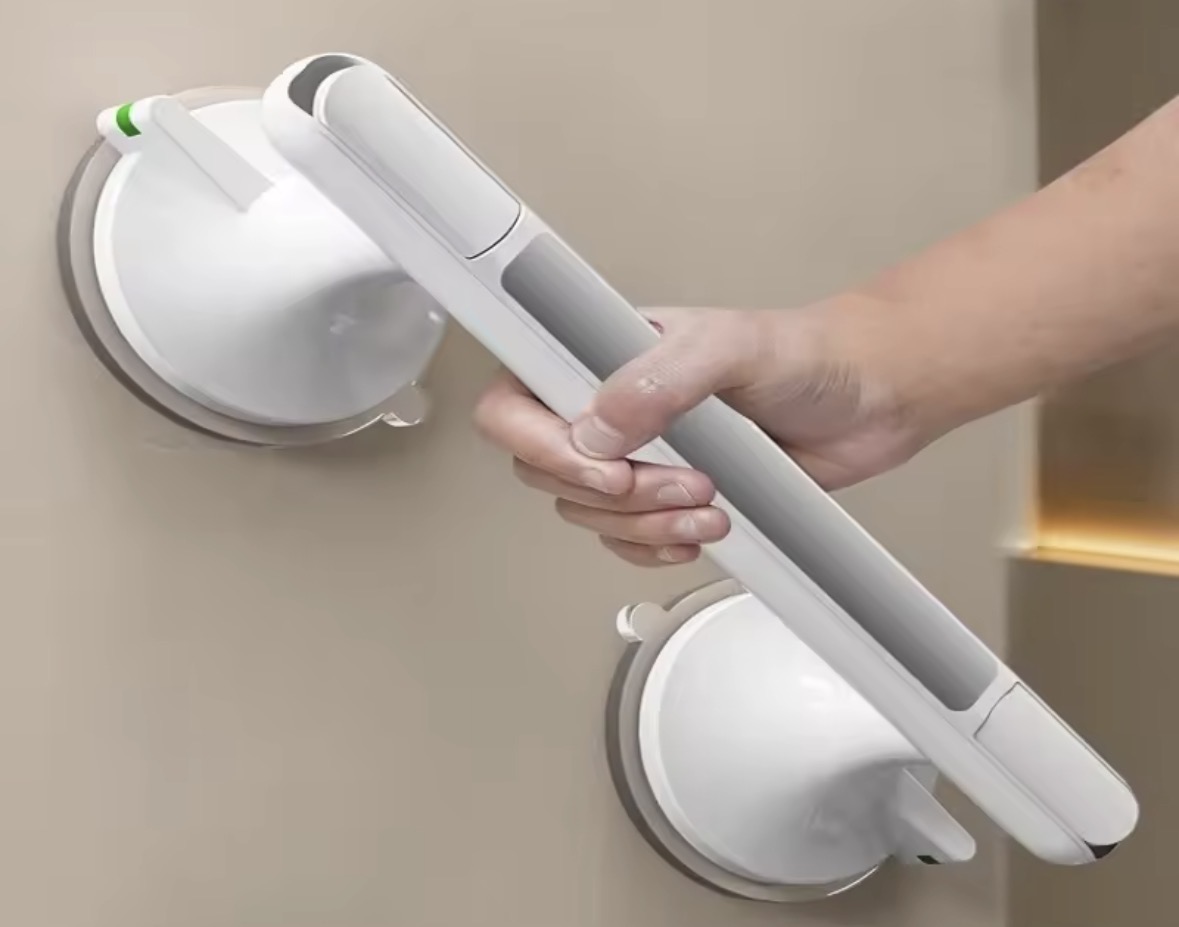 Suction grab bar mounted on a bathroom wall with a hand gripping it