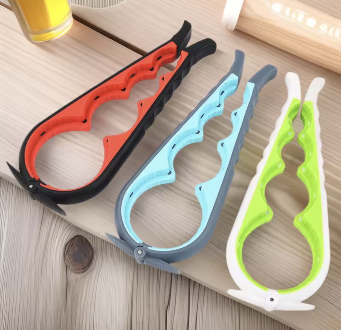Three colourful wide-grip jar and bottle opening tools on a wooden bench